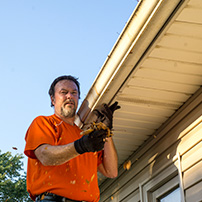 Man cleaning up installed rain gutters in fall 