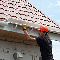 Worker Using Gutter Hangers to Install Rain Gutter System