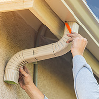 A Person Installing a White Downspout on a Rain Gutter