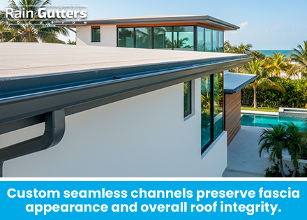 An elevated shot showing a sleek, continuous 6-inch seamless aluminum box gutter matching the dark trim of a modern coastal home with zero water staining on soffits.