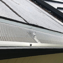 Man cleaning a clogging rain gutter installation